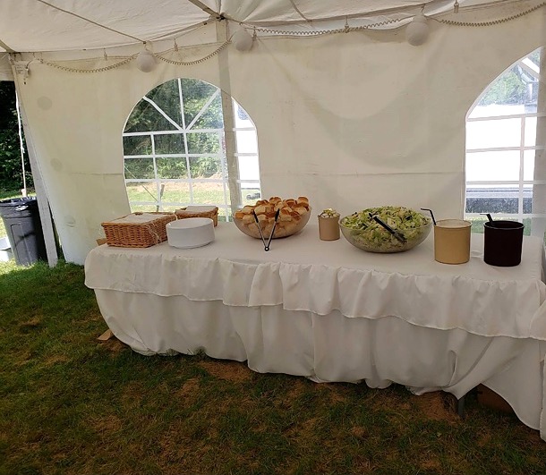 A buffet table prepared beneath an event tent